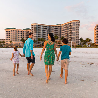 Family walks on the beach at sunset